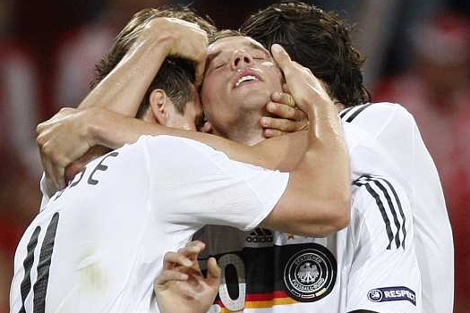 Lukas Podolski přijímá gratulace od spoluhráčů.