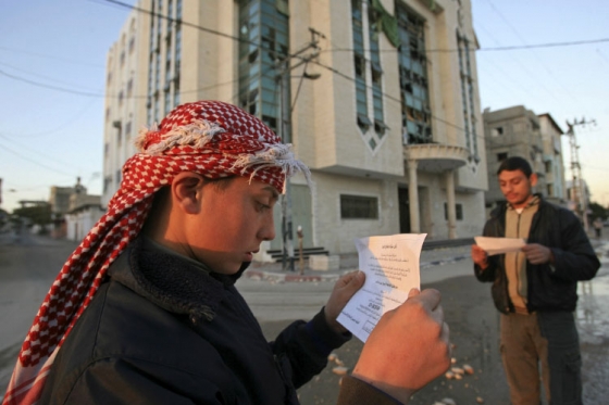 Palestinci čtou letáky. Výzývají je k opuštění oblasti před útokem. Palestinci čtou letáky. Výzývají je k opuštění oblasti před útokem.