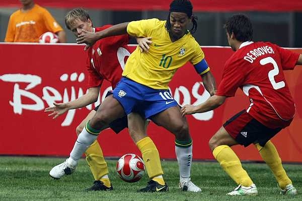 Hvězdný Brazilec Ronaldinho v sevření dvou Belgičanů.