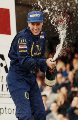 Colin McRae slaví své vítězství v RAC rallye 1995.
