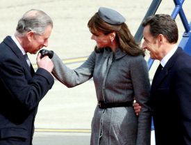 Welcome. Princ Charles líbá ruku paní Sarkozyové po příletu do Lodýna.