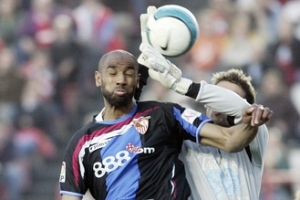 Hráč Sevilly Frederic Kanoute v souboji o míč s brankářem Gimnasticu Tarragonna Albanem Benjaminem během utkání španělské ligy na stadionu v Tarragoně.