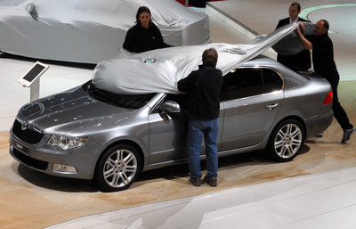 Pracovníci stánku Škoda Auto zahajují nový model vozu Škoda Superb.