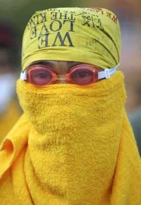 Pryč s loutkovou vládou! zakuklený demonstrant v Bangkoku.