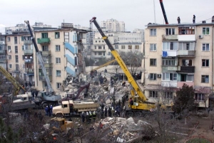 Záchranáři se snaží vyprostit za pomoci těžké techniky uvězněné lidi.