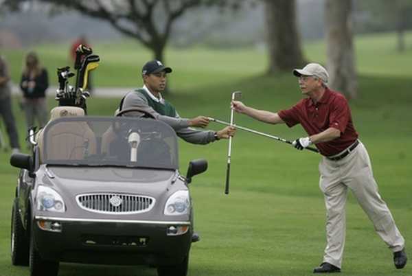 Tiger Woods (vlevo) v nové roli - podavač holí.