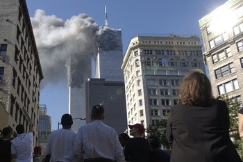 Lidé sledují jak z obou mrakodrapů newyorského Světového obchodního střediska (WTC) stoupá kouř poté, co se WTC 11. září stalo jedním z cílů koordinovaných teroristických útoků.